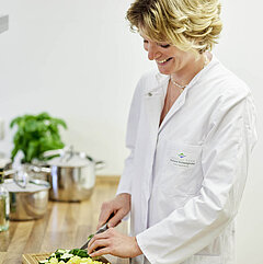 Eine Ernährungsberaterin der orthopädischen Reha schneidet Gemüse.