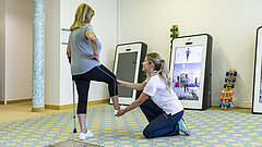 Eine Medical Park Mitarbeiterin unterstützt eine Medical Park Patientin beim Bein heben.