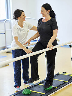 Eine Patientin der orthopädischen Reha zusammen mit einer Medical Park Therapeutin während einer Gleichgewichtsübung.