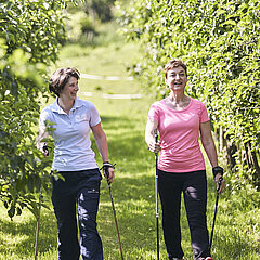 Zwei Medical Park Patientinnen gehen gemeinsam spazieren in der idyllischen Umgebung der orthopädischen Reha. 